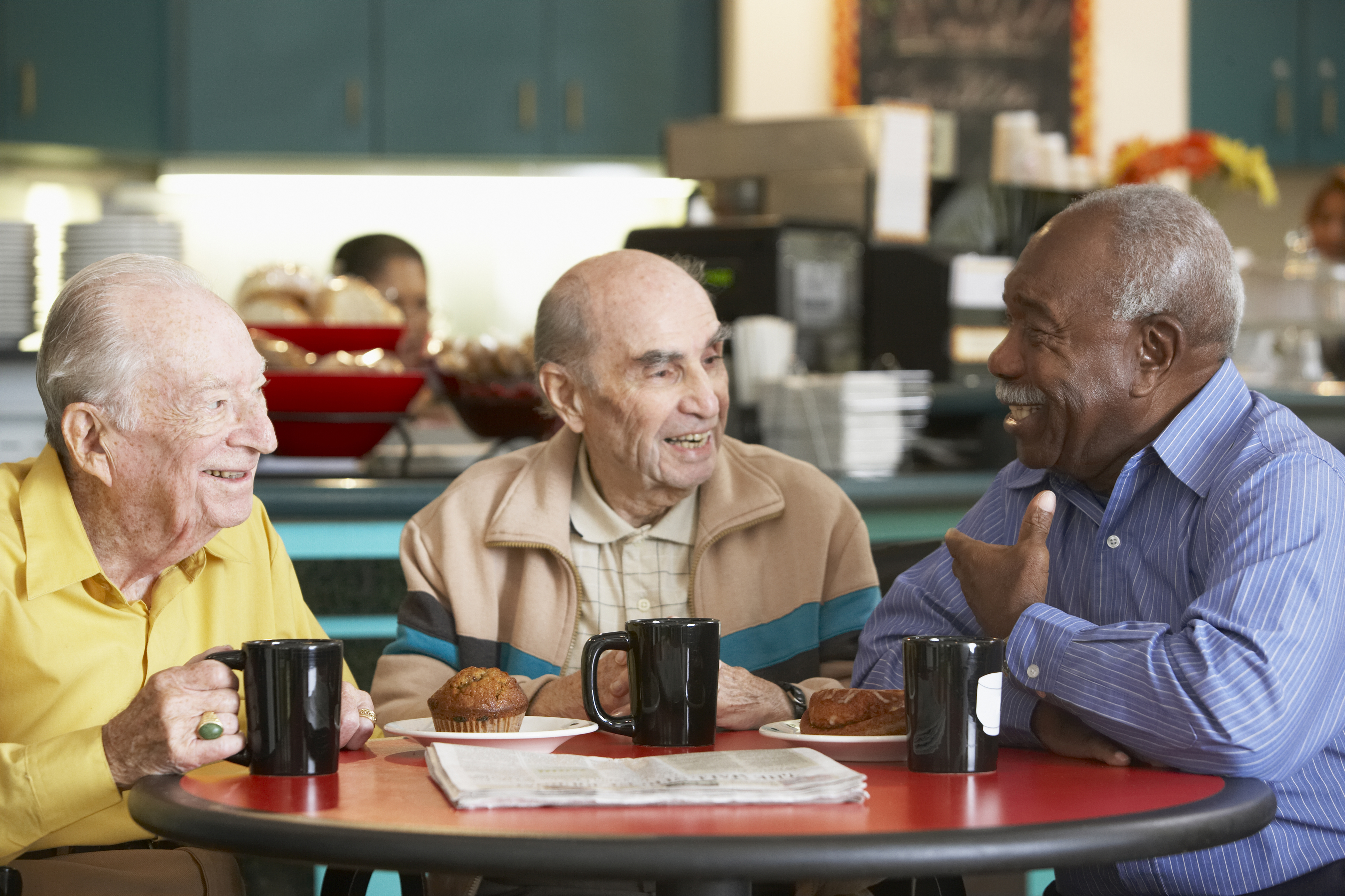 three men chat around a table in a coffee shop