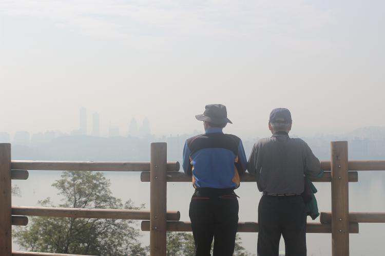 two men look out at air pollution over a city