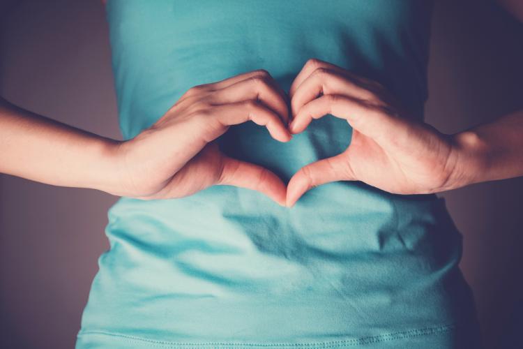 Woman hands heart sign over stomach