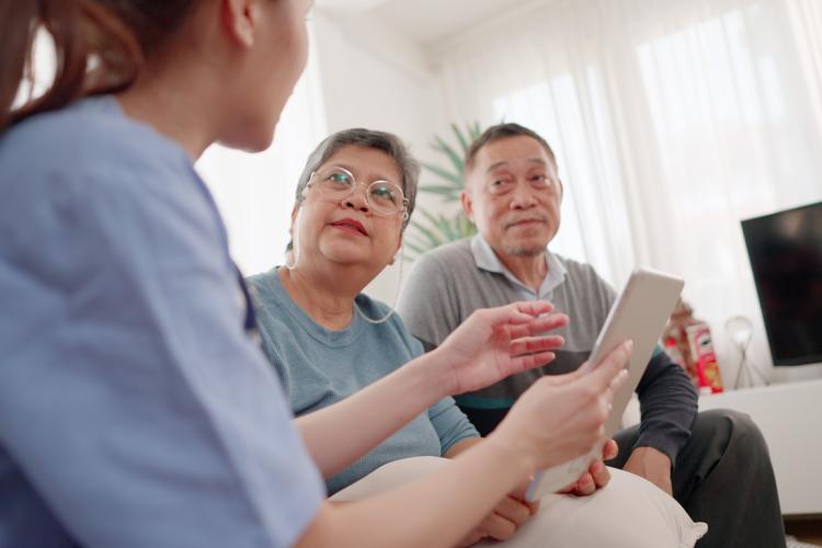 Woman talking to asian older people with ipad in hand