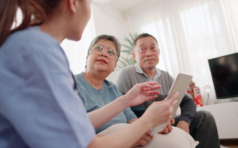 Woman talking to asian older people with ipad in hand